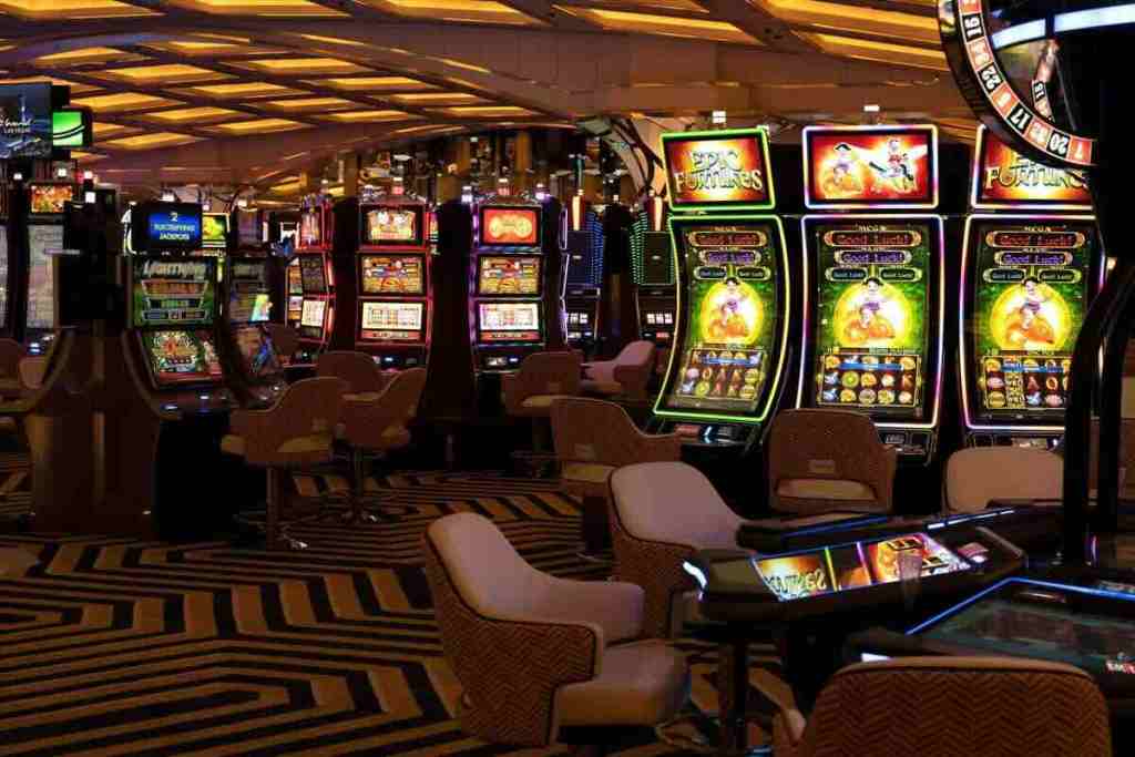 Interior of a casino with various brightly lit slot machines and gaming chairs.